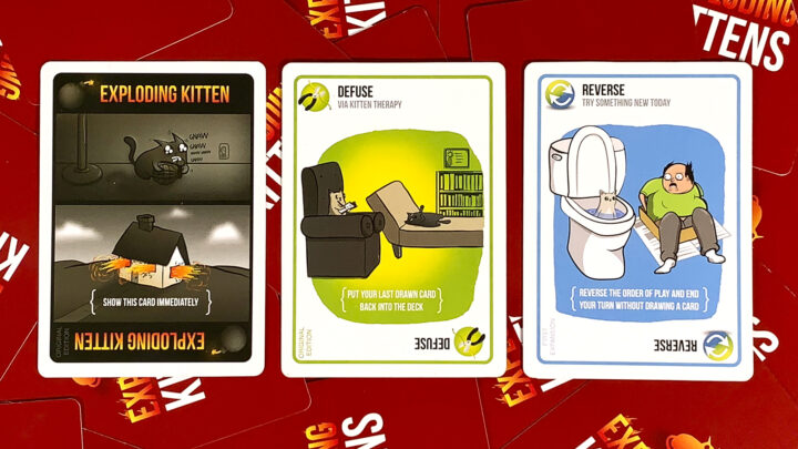 Drei Spielkarten aus dem Kartenspiel Exploding Kittens. Eine Bombe, ein Entschärfer und eine Aktiosnkarte.